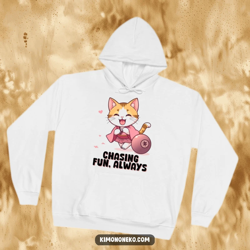 Funny kawaii calico cat in a pink kimono, chasing a rolling ball, on a soft and funny hoodie, a fun gift.