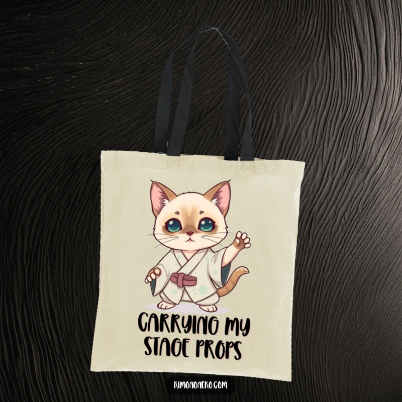 Funny kawaii Siamese cat in a silk kimono striking a dramatic pose on a tote bag, a humorous and theatrical anime accessory.